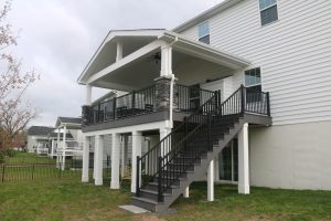 Timbertech PVC Castle Gate deck, A-frame roof with open gable and stone columns, black American series aluminum railings, posts &#038; beams covered with white vinyl &#8211; Chalfont PA