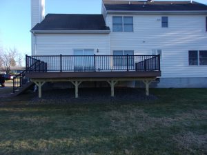 Timbertech PVC Mahogany deck with black Aluminum railings, under deck landscaped with weed blocker fabric and stones