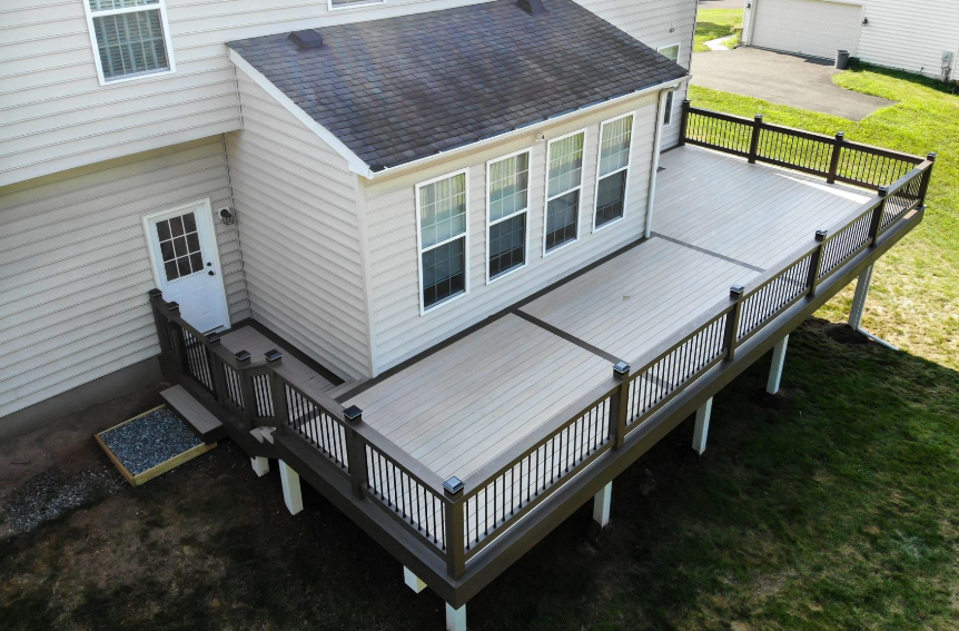 tan house with wooden deck, with brown handrails and guardrails