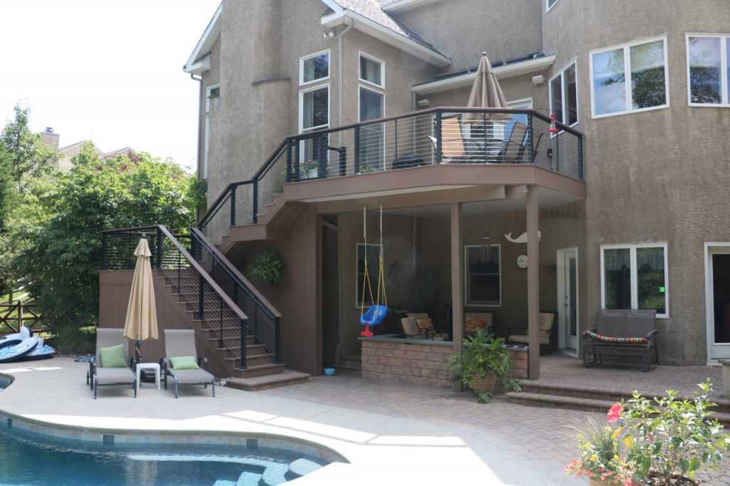 Tan house with brown curved deck with stairs